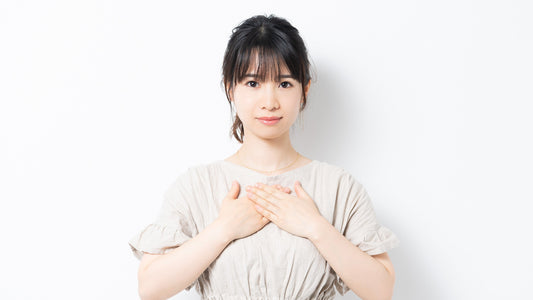 Woman with hands on chest, light background, natural fertility and wellness concept