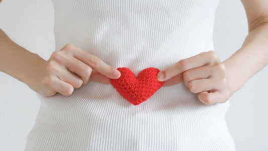 Woman holding red knitted heart over abdomen, symbolizing fertility and conception