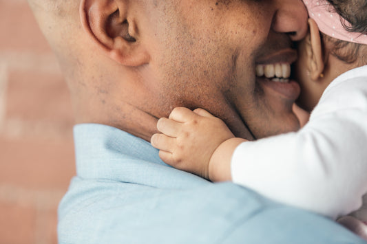Close-up of baby girl's hands hugging father's neck, family bonding, parent-child love