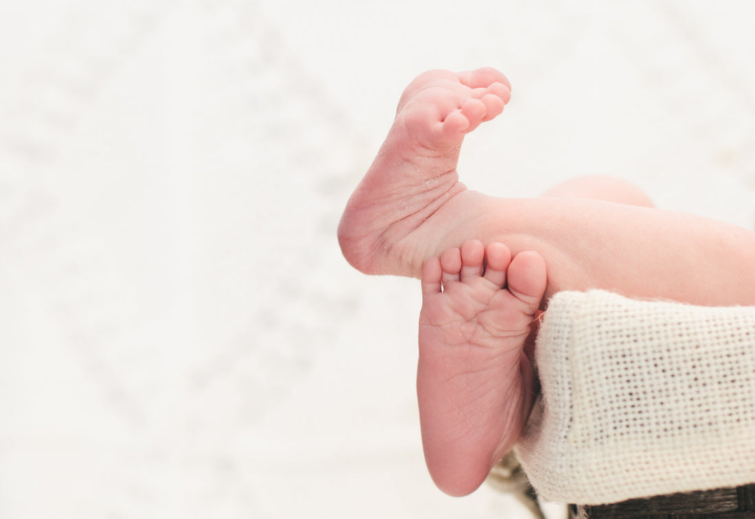 Close-up of newborn baby feet resting on a soft white blanket, fertility and conception concept