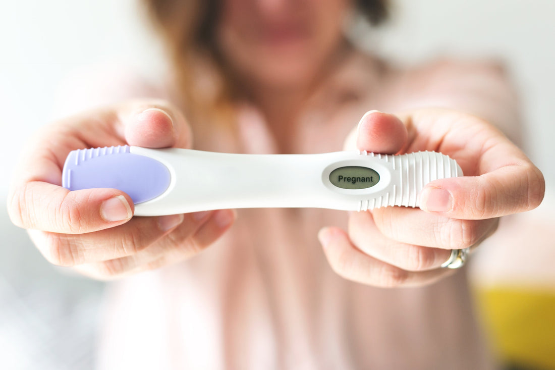 Woman holding digital pregnancy test showing positive result