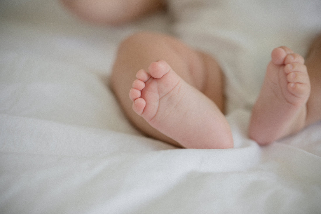 Close-up of baby feet resting on a soft white sheet, symbolizing new life and fertility.